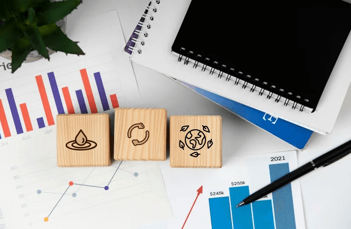 Wooden blocks with sustainability icons next to charts and graphs